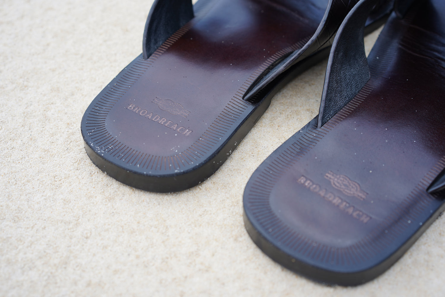 Close-up image of men’s leather Lagoon sandals by BroadReach resort wear against sand backdrop.